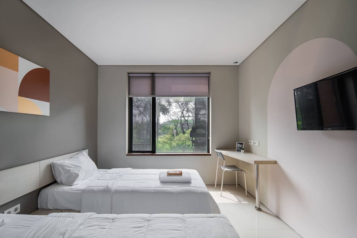 Ein modernes Schlafzimmer mit Bett, Schreibtisch und Fernseher.