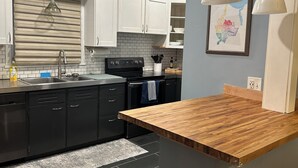 A modern kitchen with white cabinets, a black stove, and a wooden countertop. - Whole house - Park Ave 3 bedroom, enjoy all the neighborhood has to offer! (Rochester)
