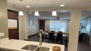 A modern kitchen with a double sink, wooden cabinets, and pendant lighting. - Beautiful Downtown Condo! Steps away from the best dining in town! (Tallahassee)
