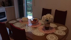 A dining table with lace placemats, a vase with flowers, and a bowl of fruit. - Spacious and Cozy Apartments Dugi Rat (Dugi Rat)