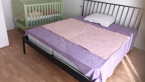 A bedroom with a bed, a crib, and a white wall. - Spacious and Cozy Apartments Dugi Rat (Dugi Rat)