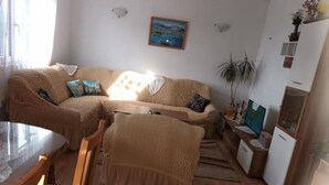 A cozy living room with a sofa, a dining table, and a small kitchenette. - Spacious and Cozy Apartments Dugi Rat (Dugi Rat)
