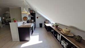 A modern kitchen with a central island, pendant lights, and a view of the dining area.