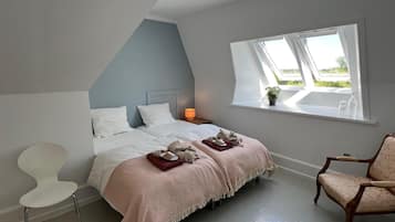 Quarto com cama, mesa de cabeceira, cadeira e janela com vista.