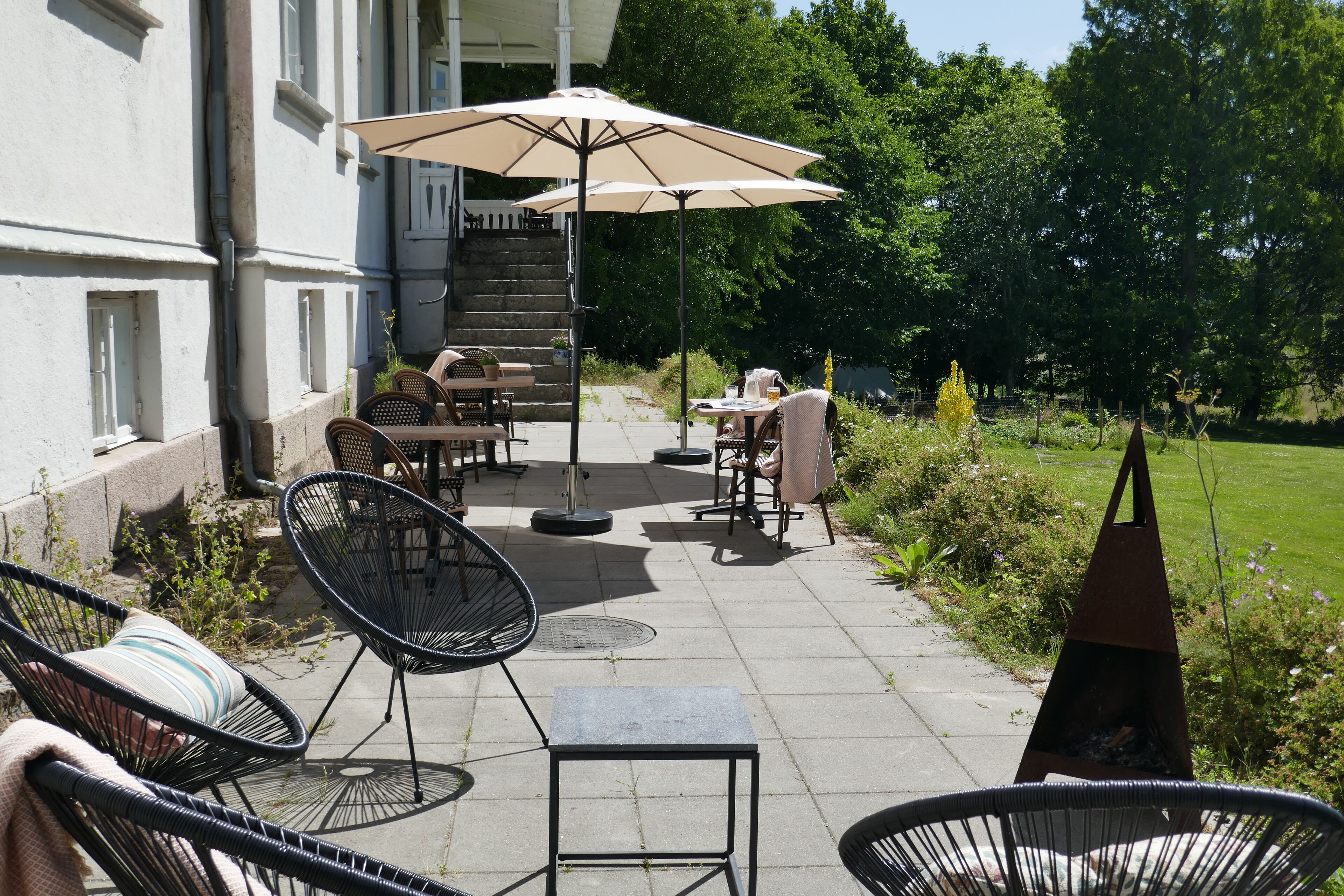 An outdoor patio with wicker chairs, a table, and an umbrella.