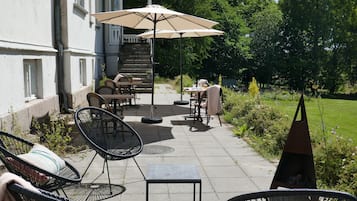 An outdoor patio with wicker chairs, a table, and an umbrella.