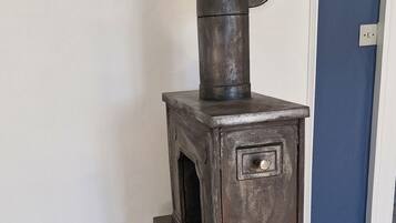A vintage stove with a chimney, a small window, and a front door.