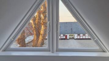 Un tragaluz triangular con vistas a un edificio y árboles desnudos.