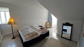 Un dormitorio con cama, una silla, una lámpara y un espejo.
