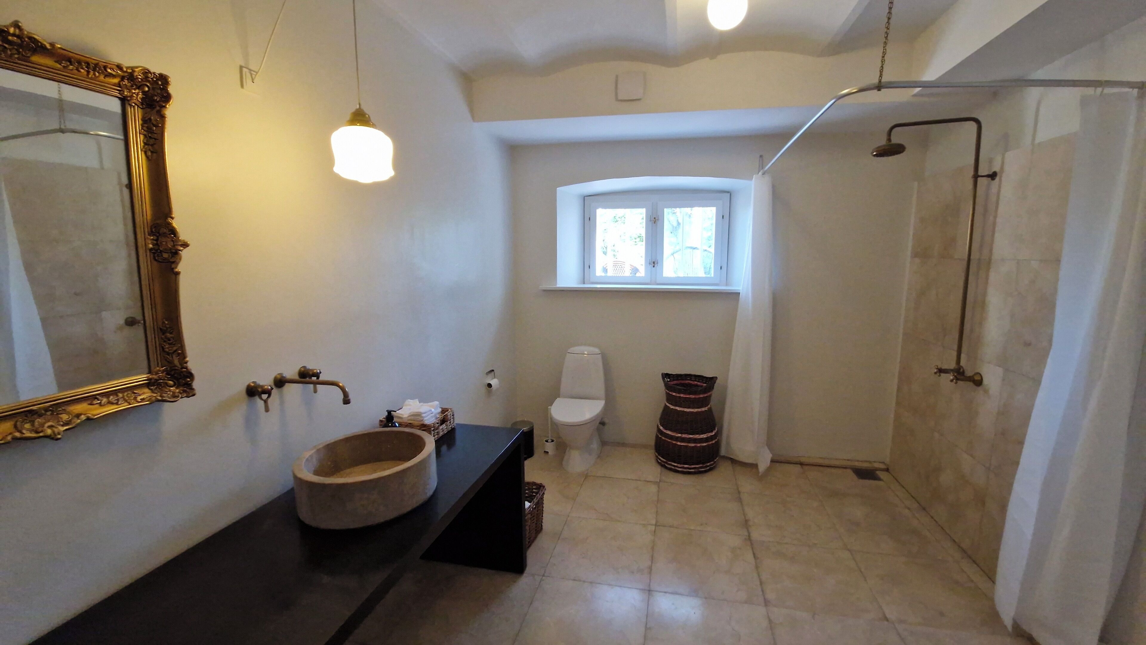A bathroom with a large mirror, a sink, a toilet, and a shower.