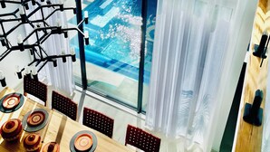 A high-ceilinged dining area with a large window overlooking a residential neighborhood. - Luxe designer house with Pool, Cinema & Gym (Clyde North)
