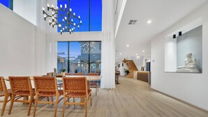 A spacious dining area with a high ceiling, wooden flooring, and a modern chandelier. - Luxe designer house with Pool, Cinema & Gym (Clyde North)