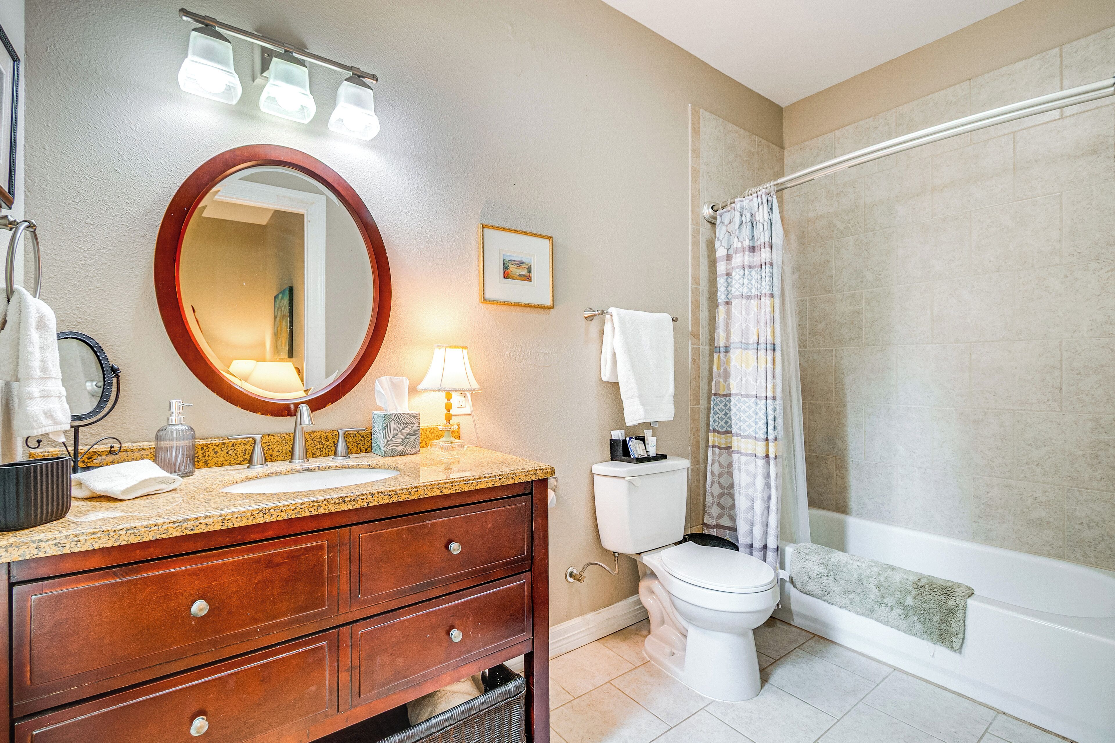 A bathroom with a sink, mirror, toilet, and shower curtain.