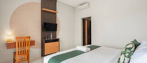 Una habitación de hotel moderna con una cama, una silla de madera, un escritorio con lámpara, un televisor y un armario.