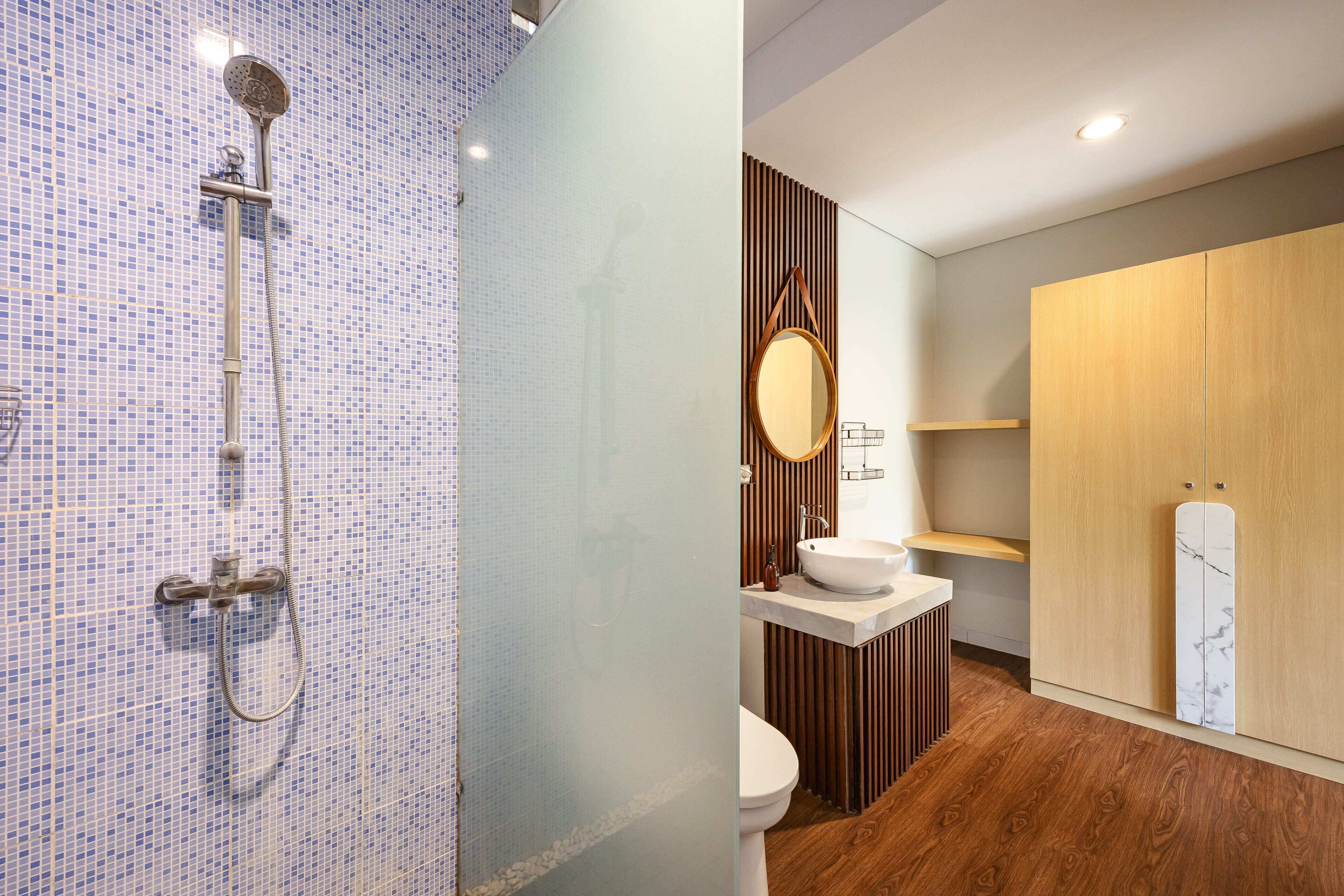 A bathroom with a shower, toilet, sink, and wooden cabinets.