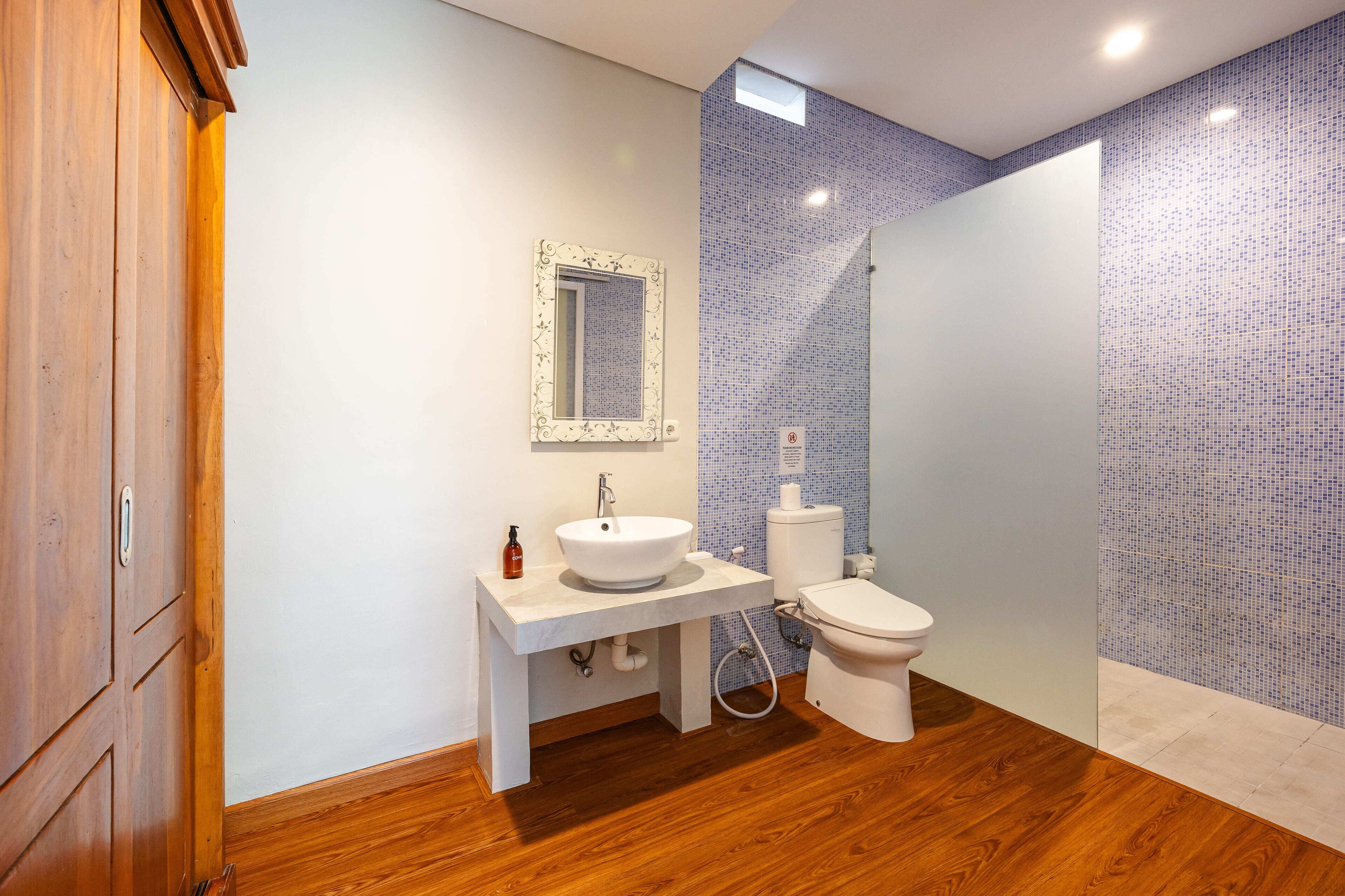 A bathroom with a wooden floor, white sink, and toilet.