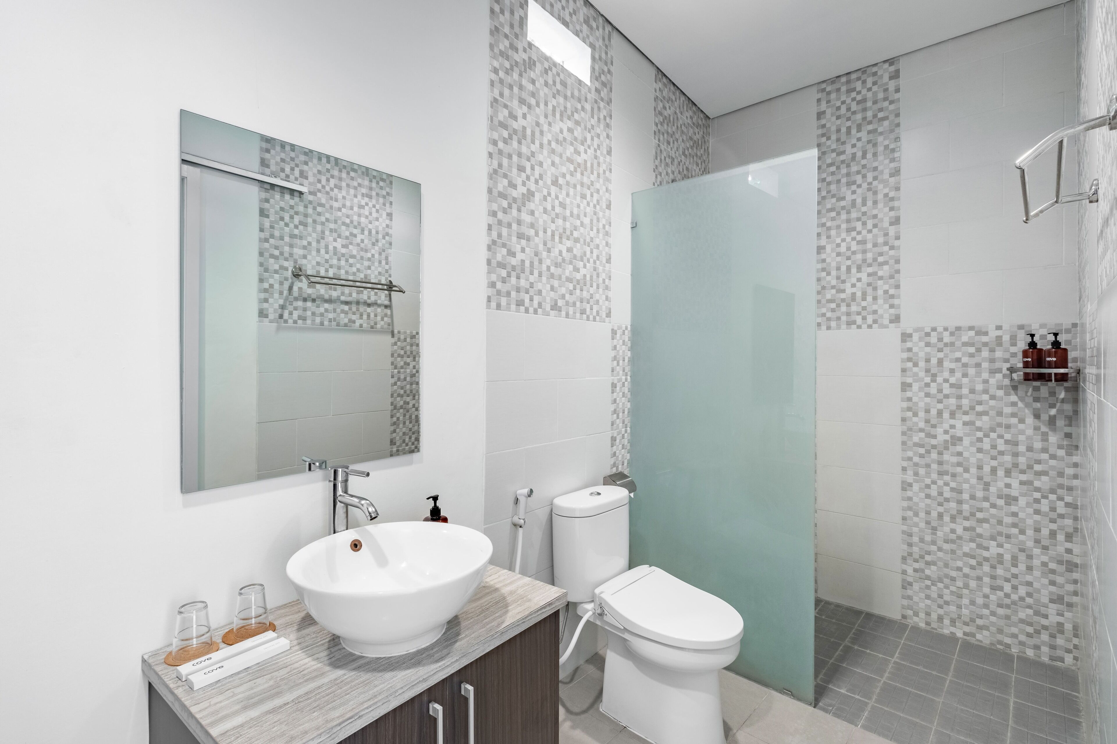 A modern bathroom with a white sink, mirror, and toilet.