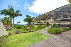 Zona residencial con césped cuidado, palmeras y vista a la montaña.
