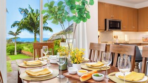 Une table à manger dressée avec des assiettes, des couverts et des verres, offrant une vue sur l’extérieur.