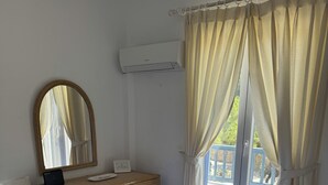 Hotelkamer met twee bedden, een bureau, een spiegel, een airconditioning en uitzicht.