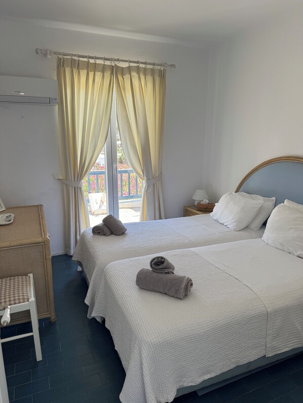 A hotel room with two beds, a desk, and a window with curtains.