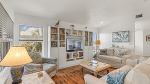 A living room with a sofa, armchair, coffee table, and a bookshelf filled with books. - Fenimore Mill 6DE Dual Delight, Two Units in One - Families/Groups/Gulf Front! (Cedar Key)