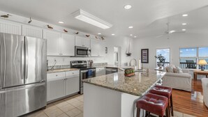 A modern kitchen with stainless steel appliances, white cabinetry, and a large island with bar stools. - Fenimore Mill 6DE Dual Delight, Two Units in One - Families/Groups/Gulf Front! (Cedar Key)