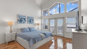 A bedroom with a large bed, two bedside tables, a TV, and a balcony with a view. - Fenimore Mill 6DE Dual Delight, Two Units in One - Families/Groups/Gulf Front! (Cedar Key)