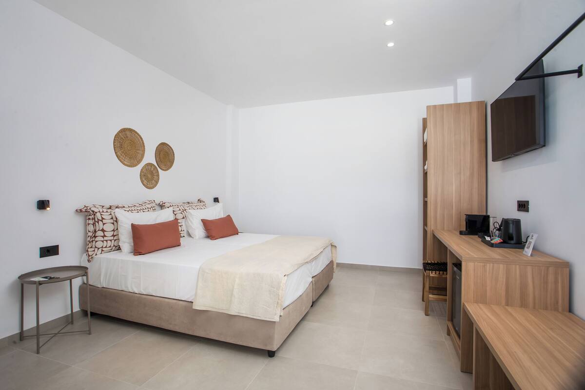 A modern bedroom with a bed, bedside table, and a desk with a chair.