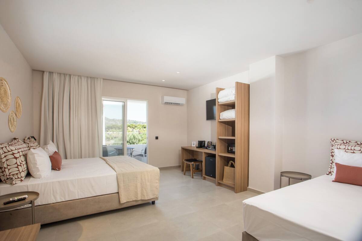 A modern hotel room with a large bed, a desk, a TV, and a wardrobe.