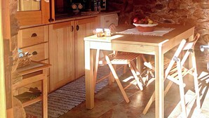 Una cucina in legno con una parete in pietra, un tavolo con sedie e una ciotola di frutta sul tavolo.