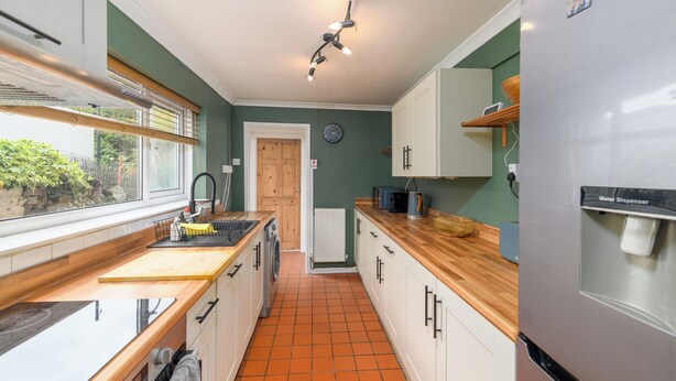 A kitchen with a wooden countertop, white cabinets, a built-in oven, and a water dispenser.