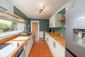 A kitchen with a wooden countertop, white cabinets, a built-in oven, and a water dispenser. - Spacious 2Bed W/Backyard near Cardiff Castle (Cardiff)