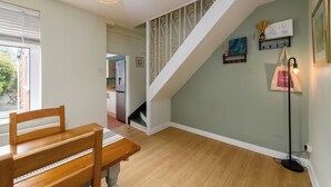 A dining area with a wooden table and chairs, a staircase with decorative railings, and a floor lamp.
