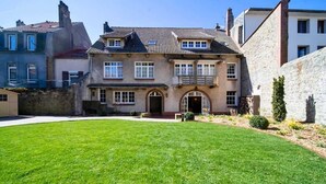 A two-story house with a front lawn, a stone wall, and a small garden.