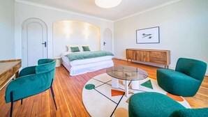 A modern bedroom with a bed, a glass coffee table, and two green armchairs.