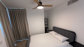 A bedroom with a bed, a nightstand, a ceiling fan, and a window with curtains.