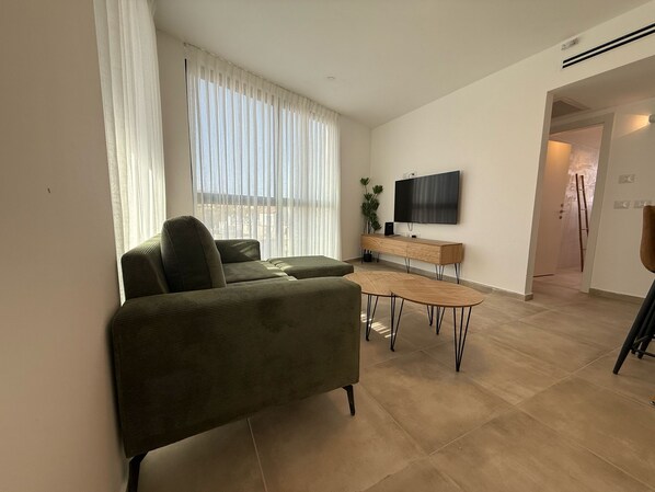 Una sala de estar moderna con un sofá, una mesa de centro y un televisor instalado en la pared.