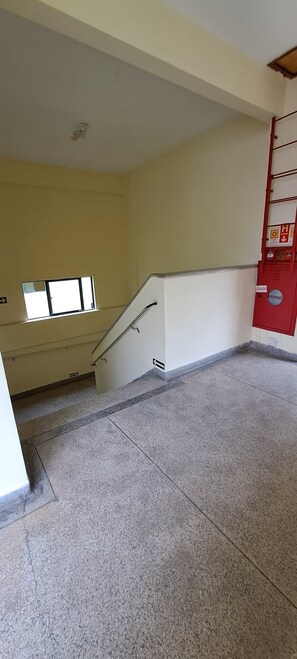 A stairwell with a handrail, a window, and a red fire extinguisher.