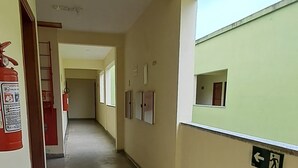 Ein Flur mit Feuerlöscher, einem Hinweisschild für einen Notausgang und einem Fenster mit Blick nach draußen.