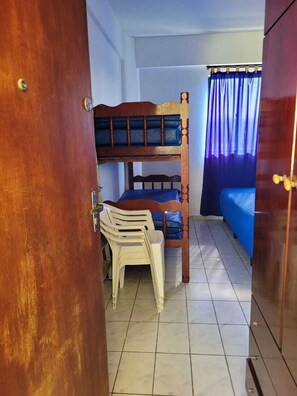 Una habitación con literas, un escritorio, una silla y un armario.