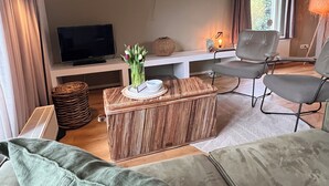 A living room with a sofa, a television, a wicker coffee table, and a chair.