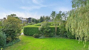 A well-maintained garden with a variety of trees and shrubs, a clear pathway, and a neatly trimmed lawn.