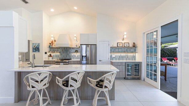 A modern kitchen with a central island, bar stools, stainless steel appliances, and a view to the outside. - Relaxing 3BR / 2BA Naples Retreat - w Private Heated Pool (Naples)