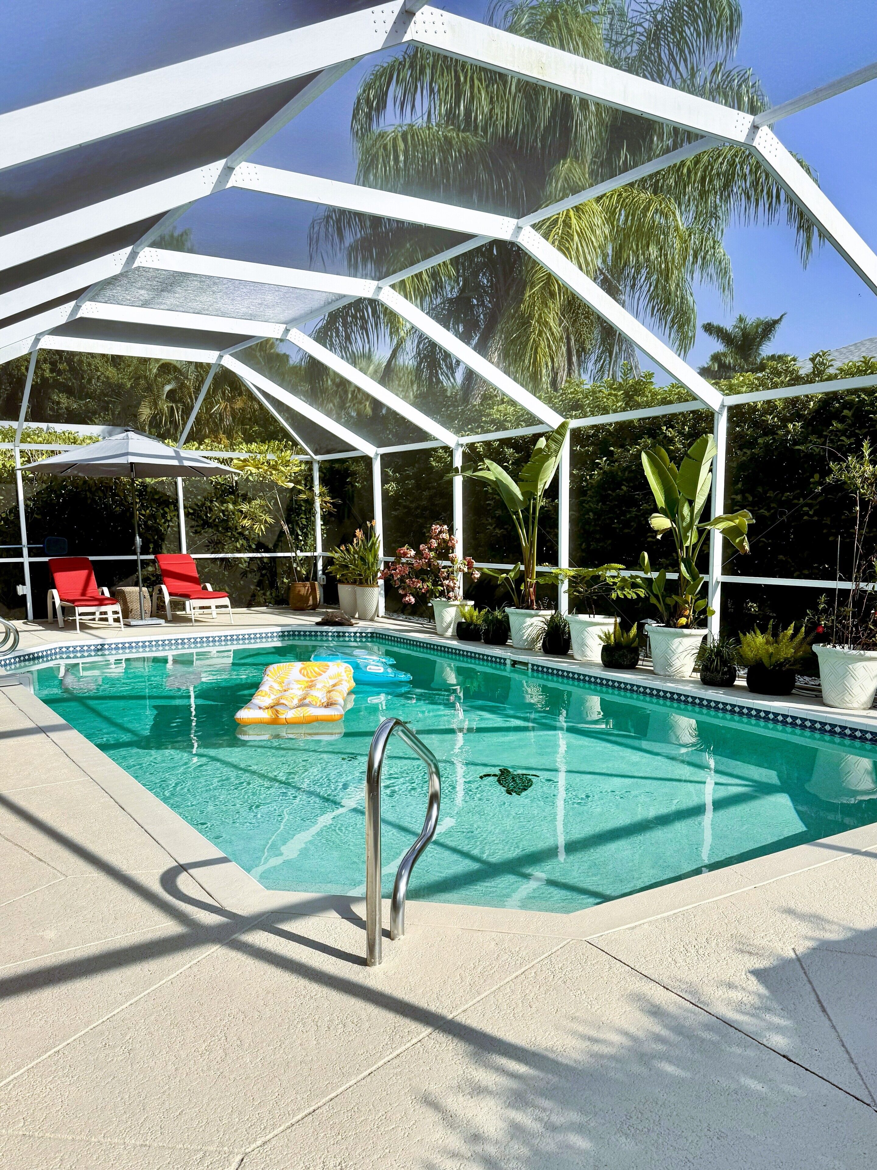 The pool deck has two lounge chairs, a sun umbrella and weber gas grill.