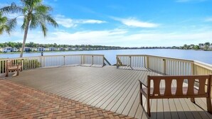 A wooden deck with a railing, benches, and a palm tree. - Relaxing 3BR / 2BA Naples Retreat - w Private Heated Pool (Naples)