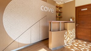 A reception desk with a 'cove' sign, wooden paneling, and a 'staff only' door. - Cove Vin Stay (Denpasar)