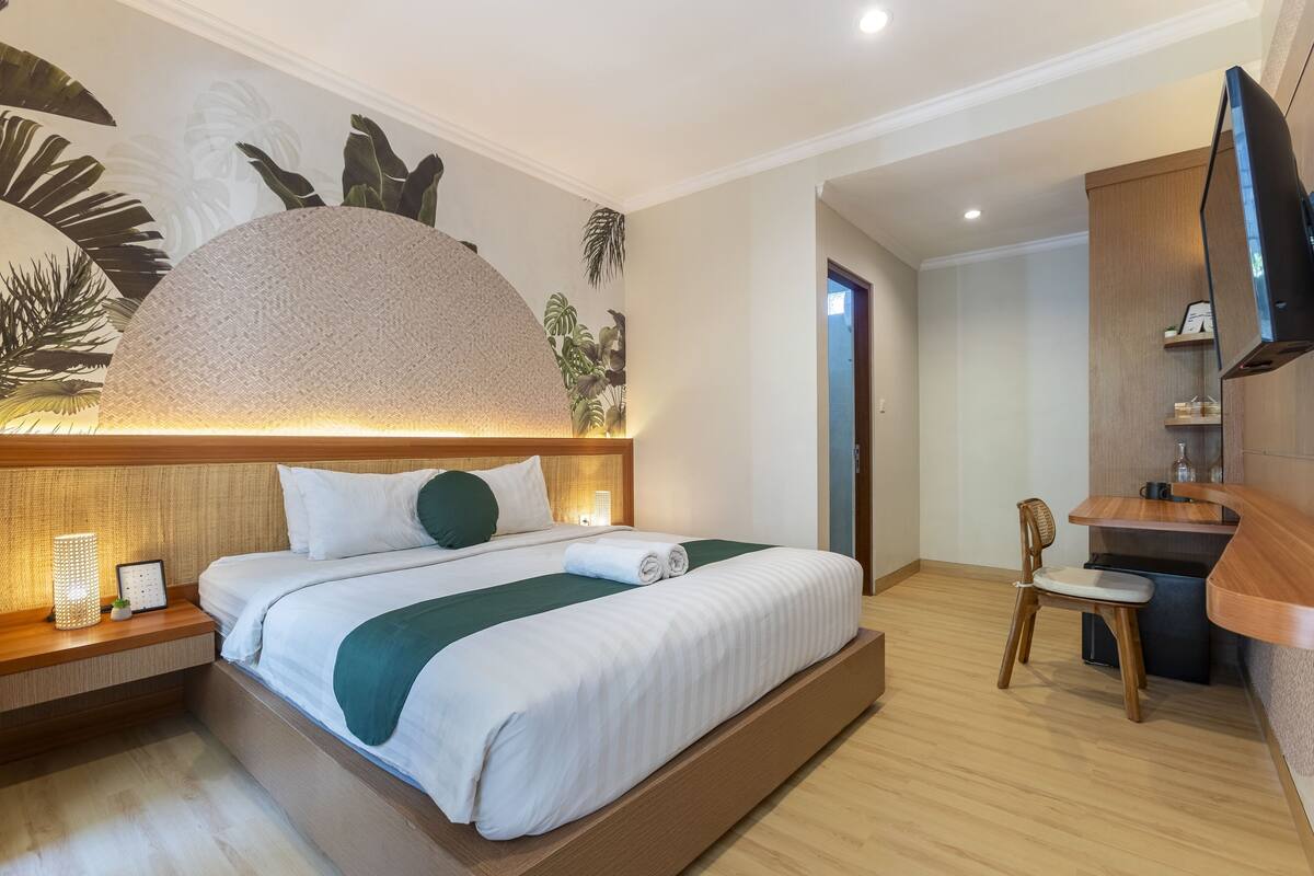 A modern hotel room with a large bed, a desk, and a television.