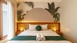 A neatly made bed with rolled towels, a large wall mural, and two bedside lamps. - Cove Vin Stay (Denpasar)