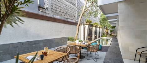An outdoor patio with tables and chairs, a small pool, and potted plants.